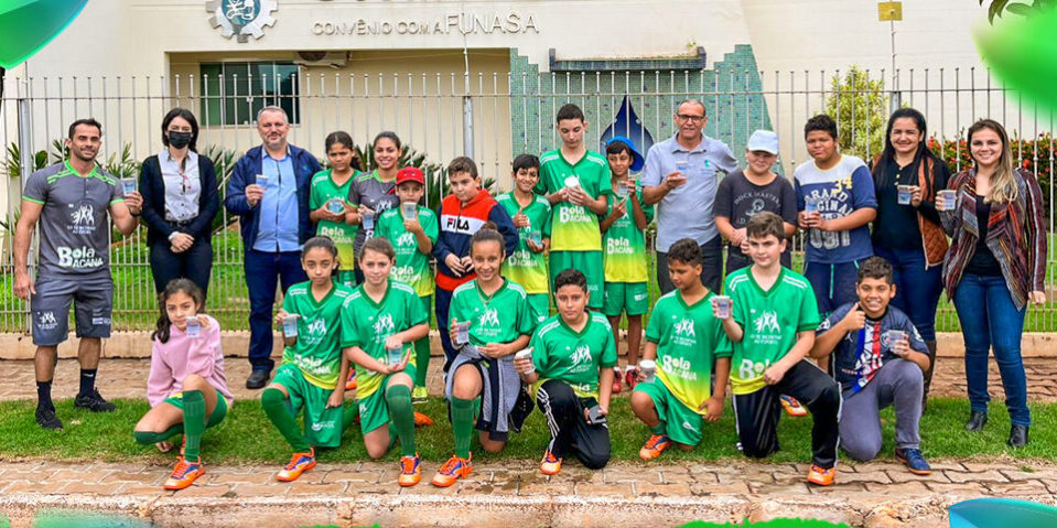 WhatsApp-Image-2022-06-14-at-18.33.36-1000×480 Alunos e alunas do projeto Bola Bacana reunidos vestindo uniforme verde, junto de alguns adultos em pé.